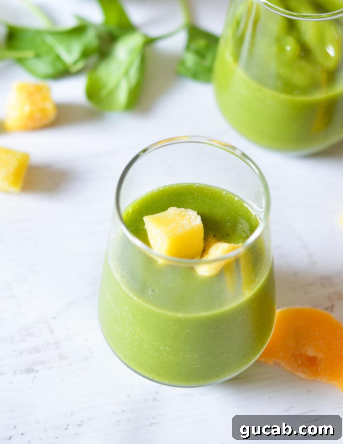 Panera's Emerald Zest Smoothie 7 A vibrant green smoothie served in a glass, topped with fresh mango slices, emphasizing its refreshing and delicious presentation.