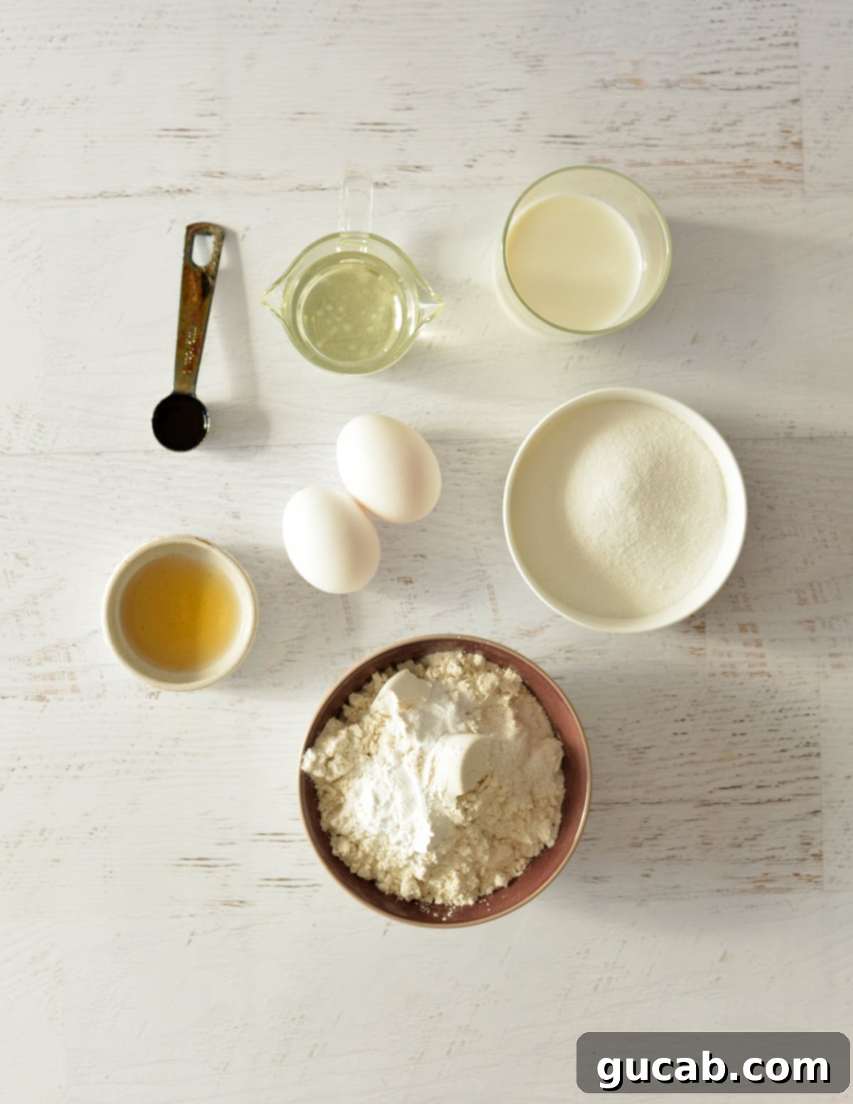 Key ingredients for gluten-free funfetti cupcakes including buttermilk, vanilla, eggs, oil, butter, flour, and sugar.