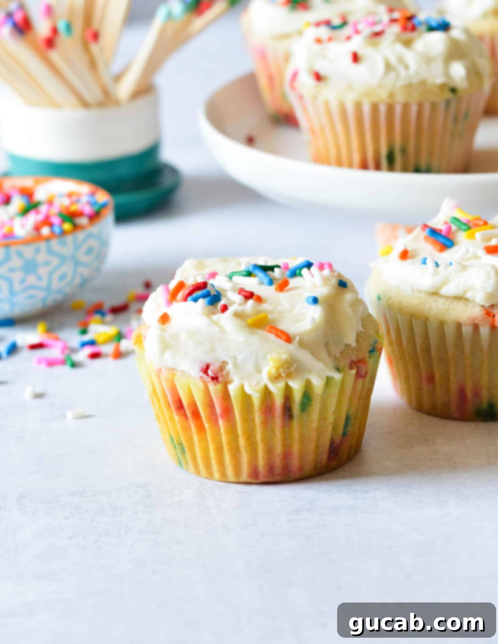 A vibrant gluten-free funfetti cupcake with a generous swirl of frosting and colorful sprinkles on top.