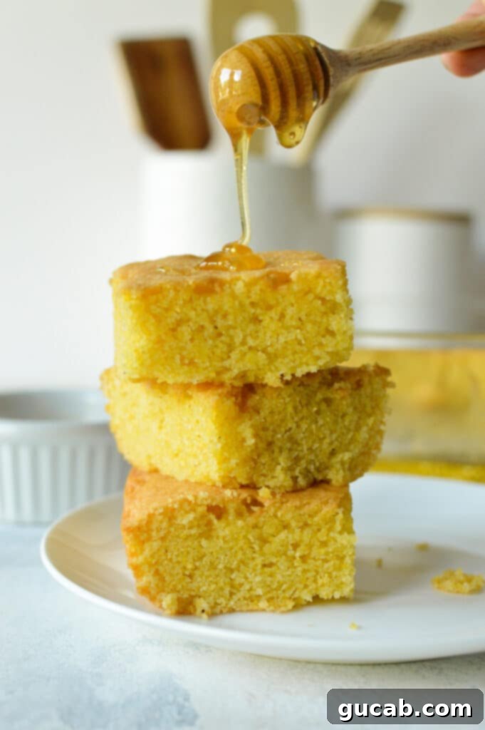 A golden-brown slice of gluten-free almond flour cornbread on a plate, showing its fluffy and moist texture.