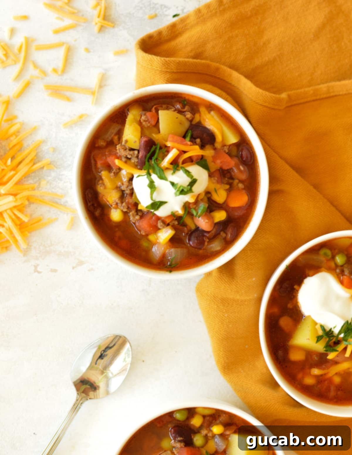 Three rustic bowls of hearty cowboy soup, topped with fresh cilantro and sour cream.