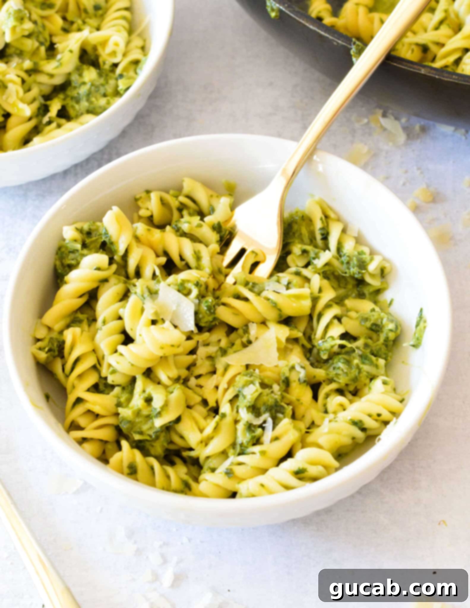 A beautifully plated bowl of creamy kale pasta, garnished with fresh parmesan cheese and a sprinkle of black pepper. The vibrant green sauce clings perfectly to the pasta.