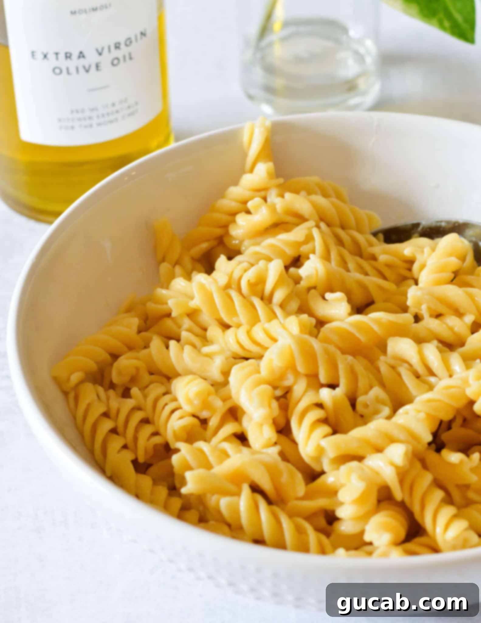A close-up shot of perfectly cooked rotini pasta in a rustic bowl, waiting to be tossed with the creamy kale sauce.