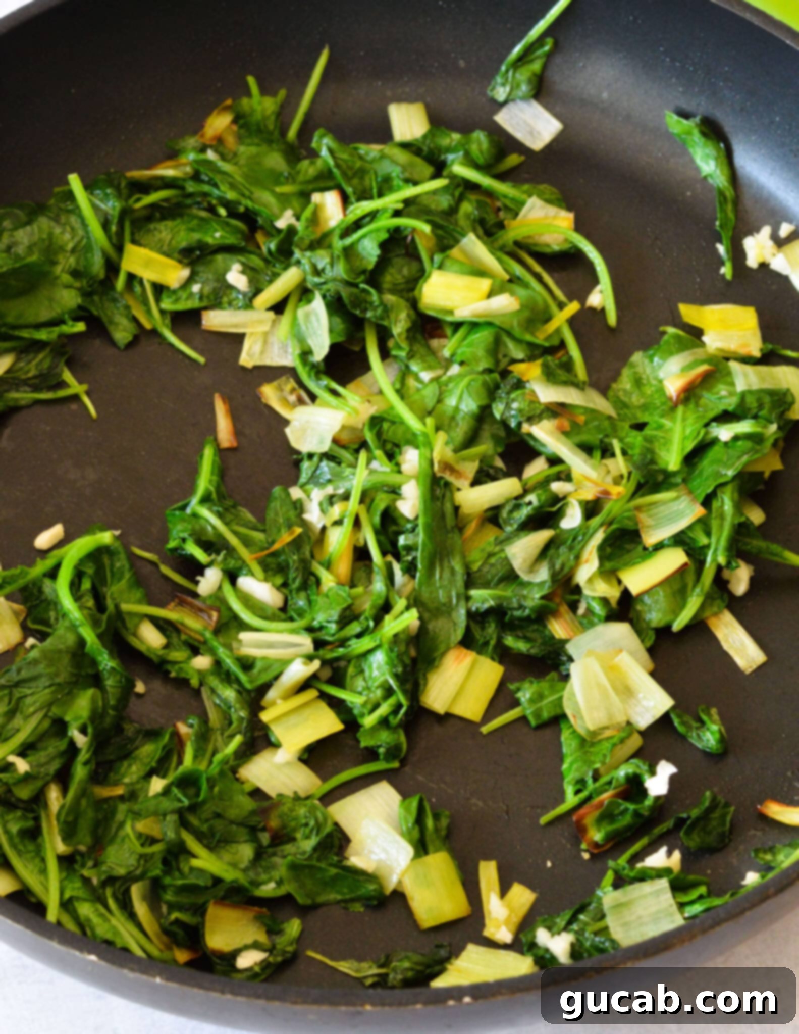 The sautéed leeks, kale, and garlic mixture after wilting down in the skillet, ready for pureeing.