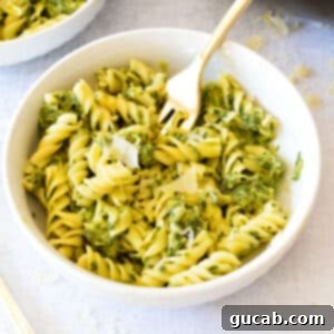 A bowl of creamy kale pasta with parmesan cheese sprinkled on top, ready to be enjoyed.