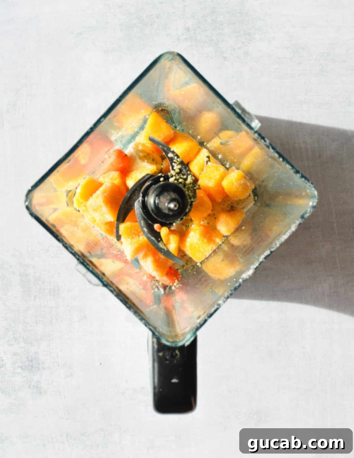 Layered ingredients: banana, carrots, and frozen mango chunks, carefully placed in a high-speed blender, ready for blending.