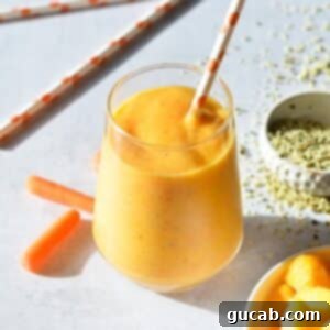 Tropical Carrot Banana Smoothie in a glass with a paper straw, ready to be enjoyed.