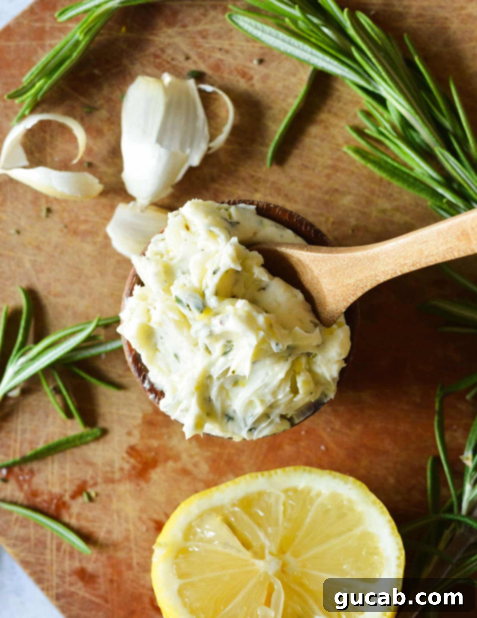 A small bowl of rosemary garlic butter with a wooden spoon in it, showcasing its rich texture and herb flecks.