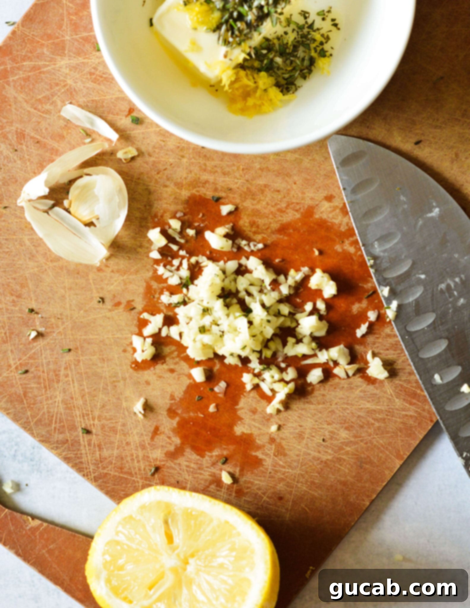 Finely minced garlic cloves on a wooden cutting board, ready to be added to the butter.