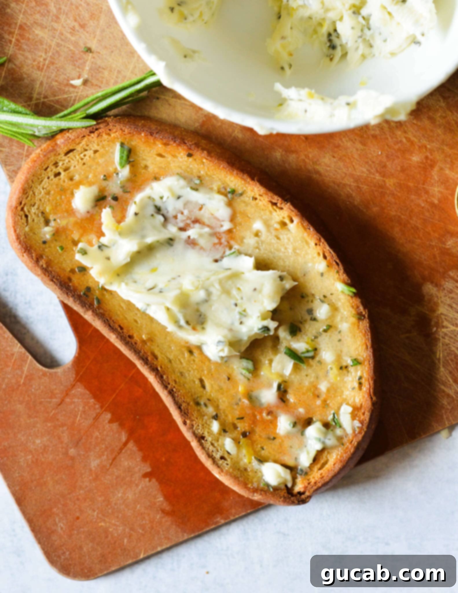 A generous dollop of herb butter spread on a slice of toasted sourdough bread, looking delicious and inviting.