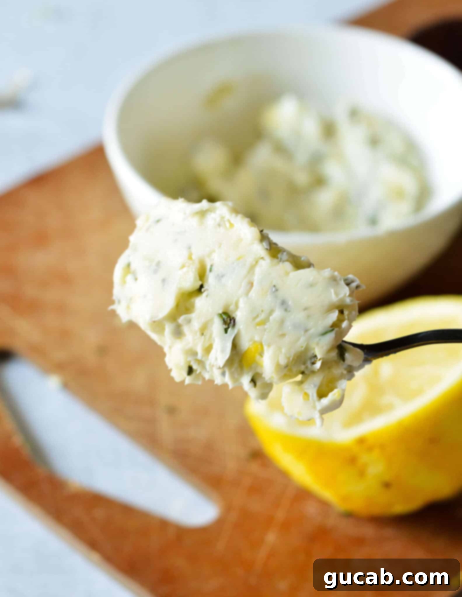 A close-up of a spoonful of creamy garlic rosemary butter, ready to be spread or melted.