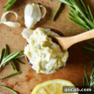 A small bowl of garlic rosemary butter with a wooden spoon in it, ready for serving.