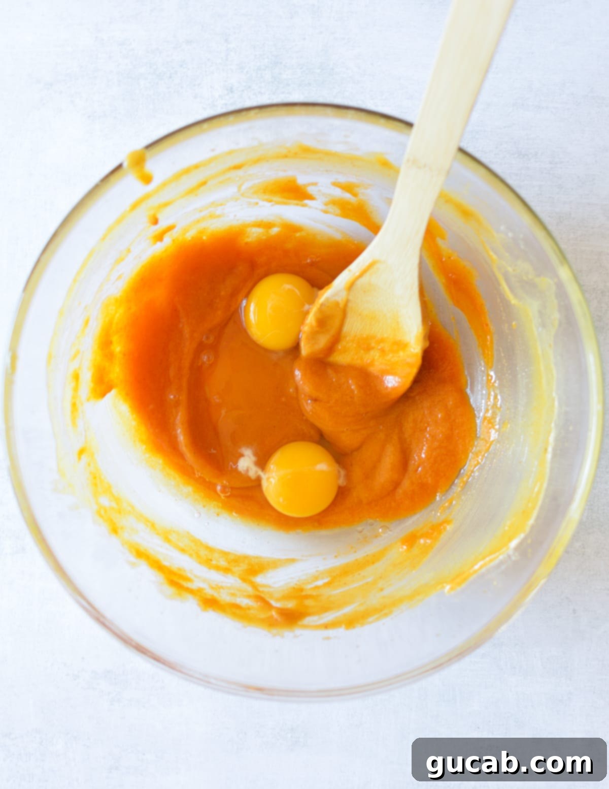 A bowl of pumpkin mixture with two fresh eggs cracked on top, awaiting a good whisking.