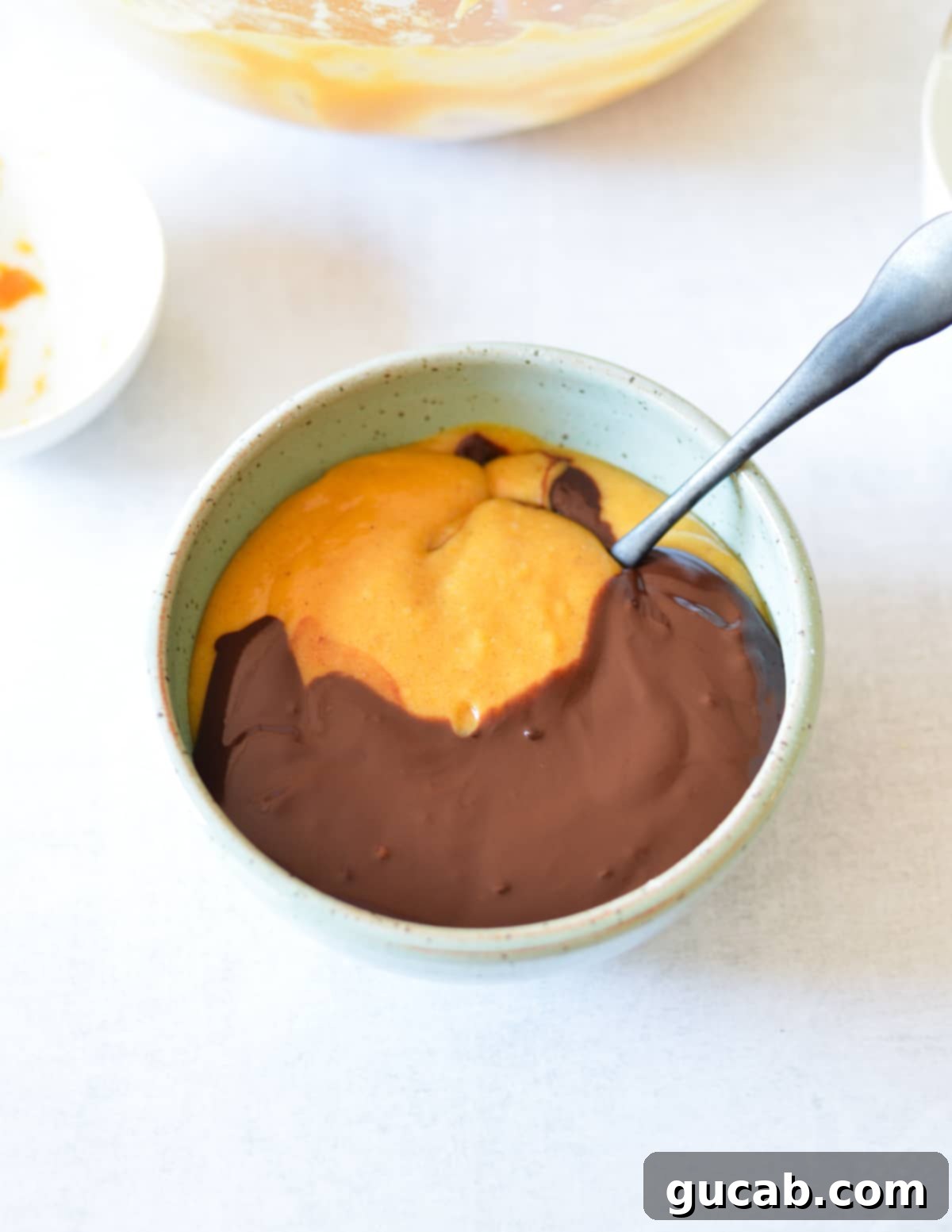 A small bowl showing pumpkin batter and melted chocolate being stirred together to create the chocolate batter.