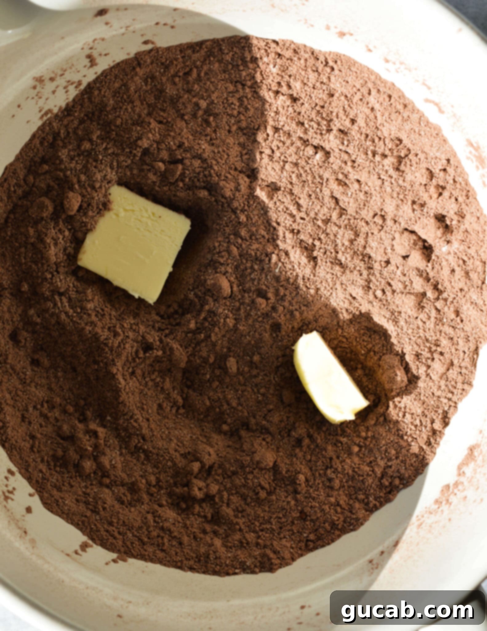 gluten free flour, sugar, and brown sugar mixed together in a bowl with two pieces of butter in it.