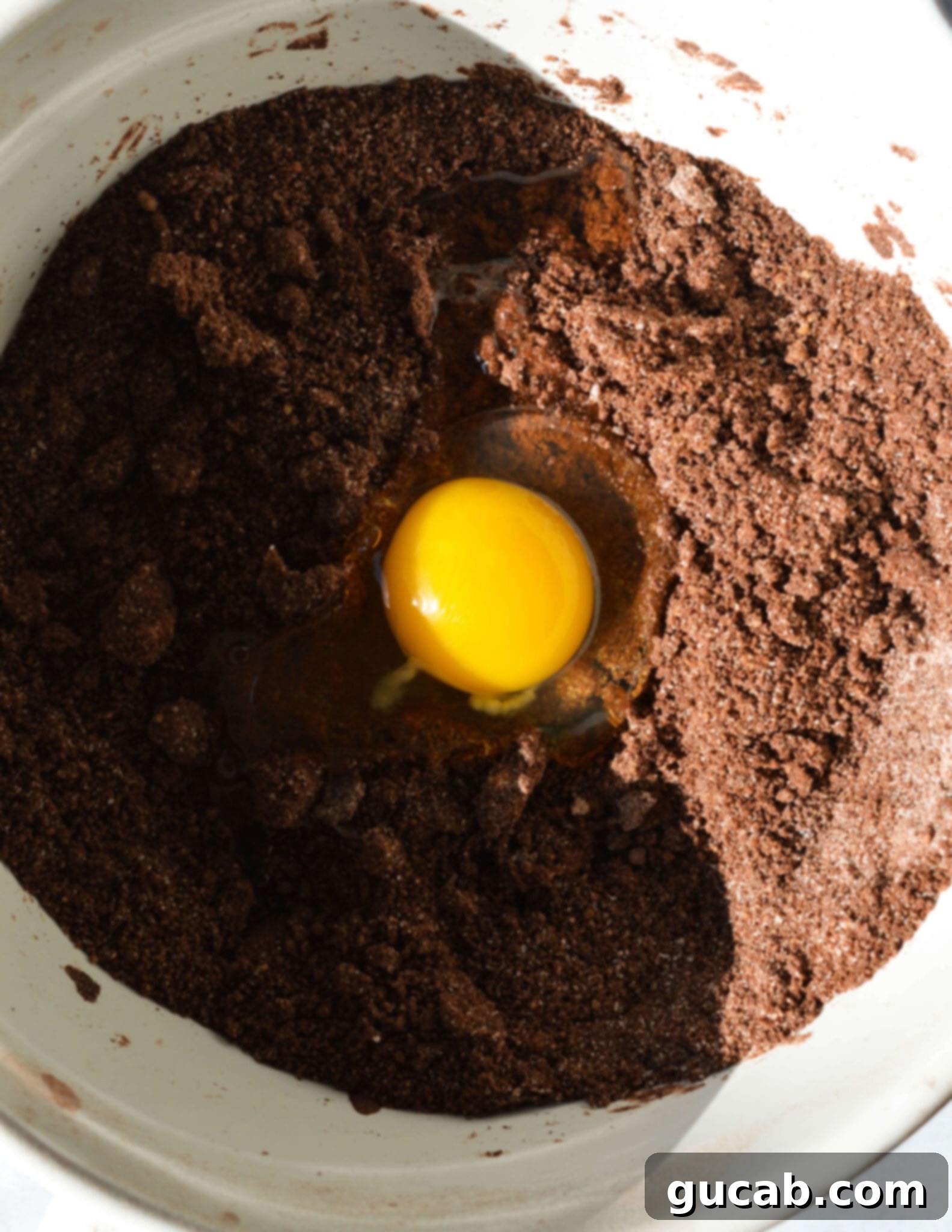 butter, flour, sugar, and cocoa powder mixed together with an egg on top.