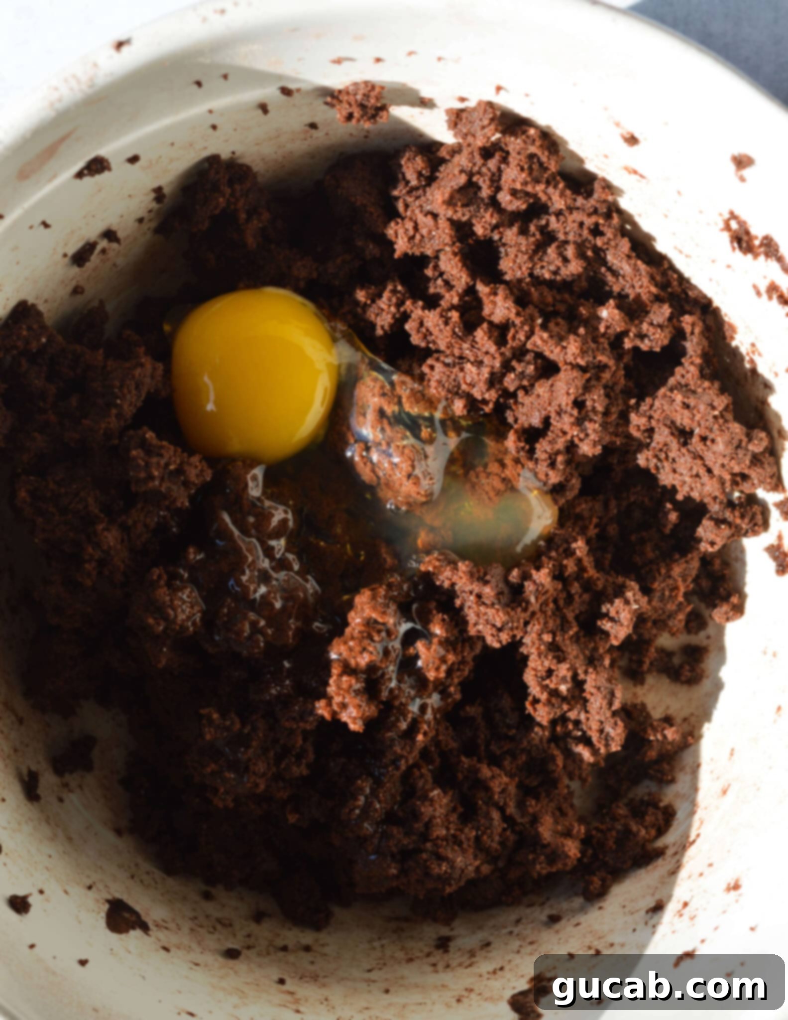 a bowl of chocolate batter with an egg on top.