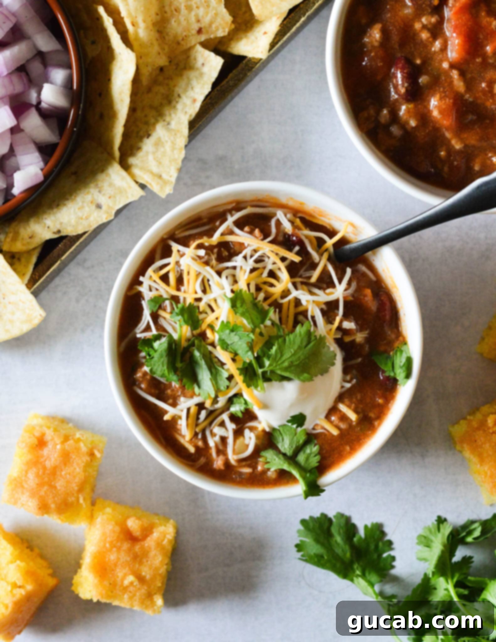 A cozy bowl of chili topped generously with shredded cheese and a sprinkle of fresh cilantro, ready to be enjoyed.