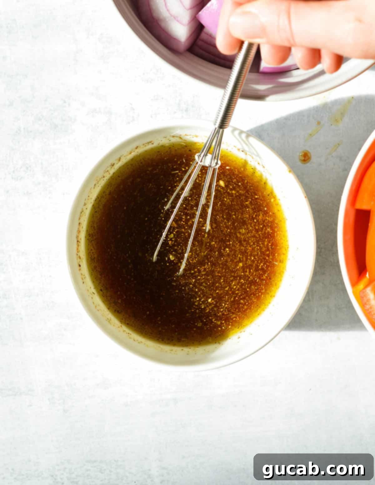 A bowl containing a simple marinade of olive oil, red wine vinegar, chipotle sauce, and oregano.