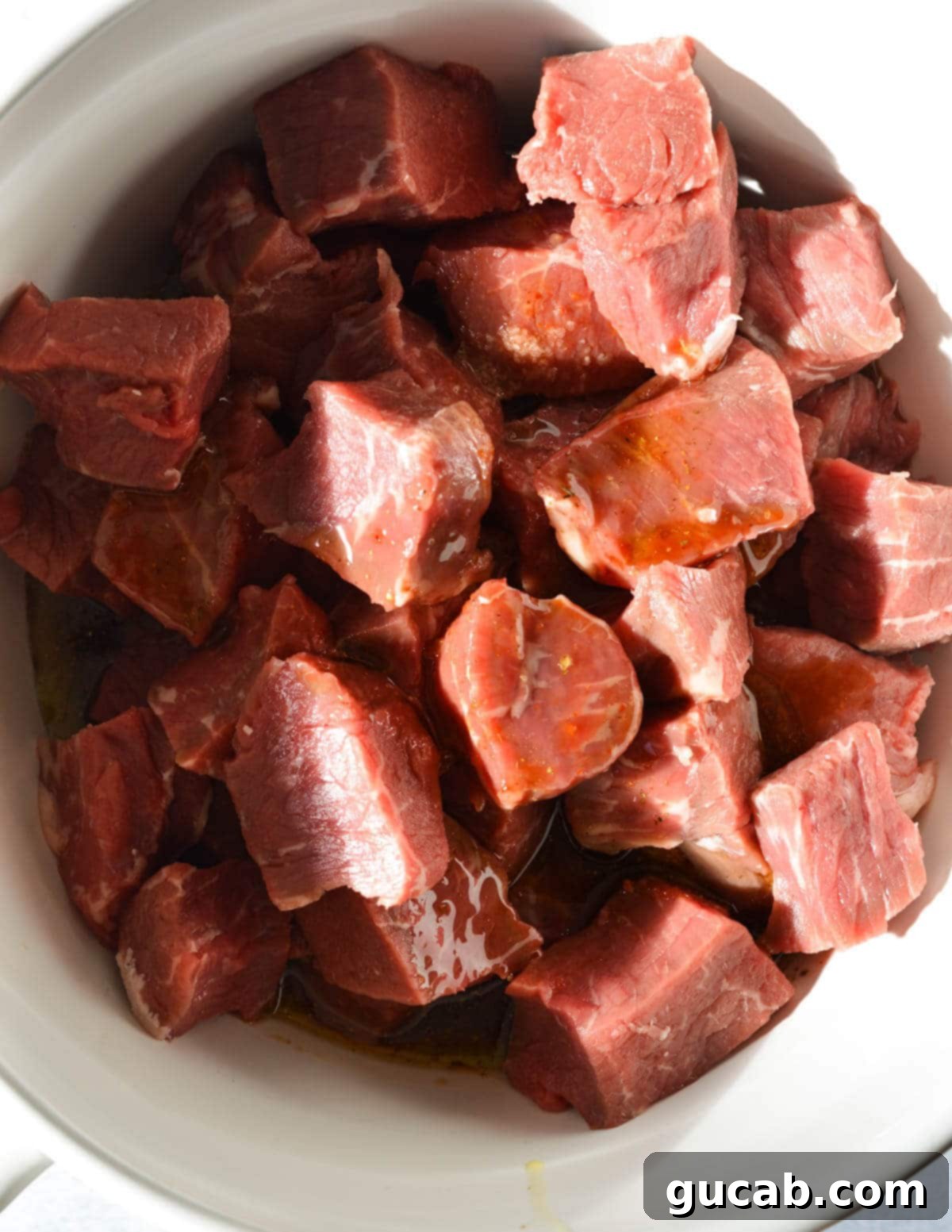 A bowl of cubed sirloin steak with the chipotle marinade poured over, ready for chilling.