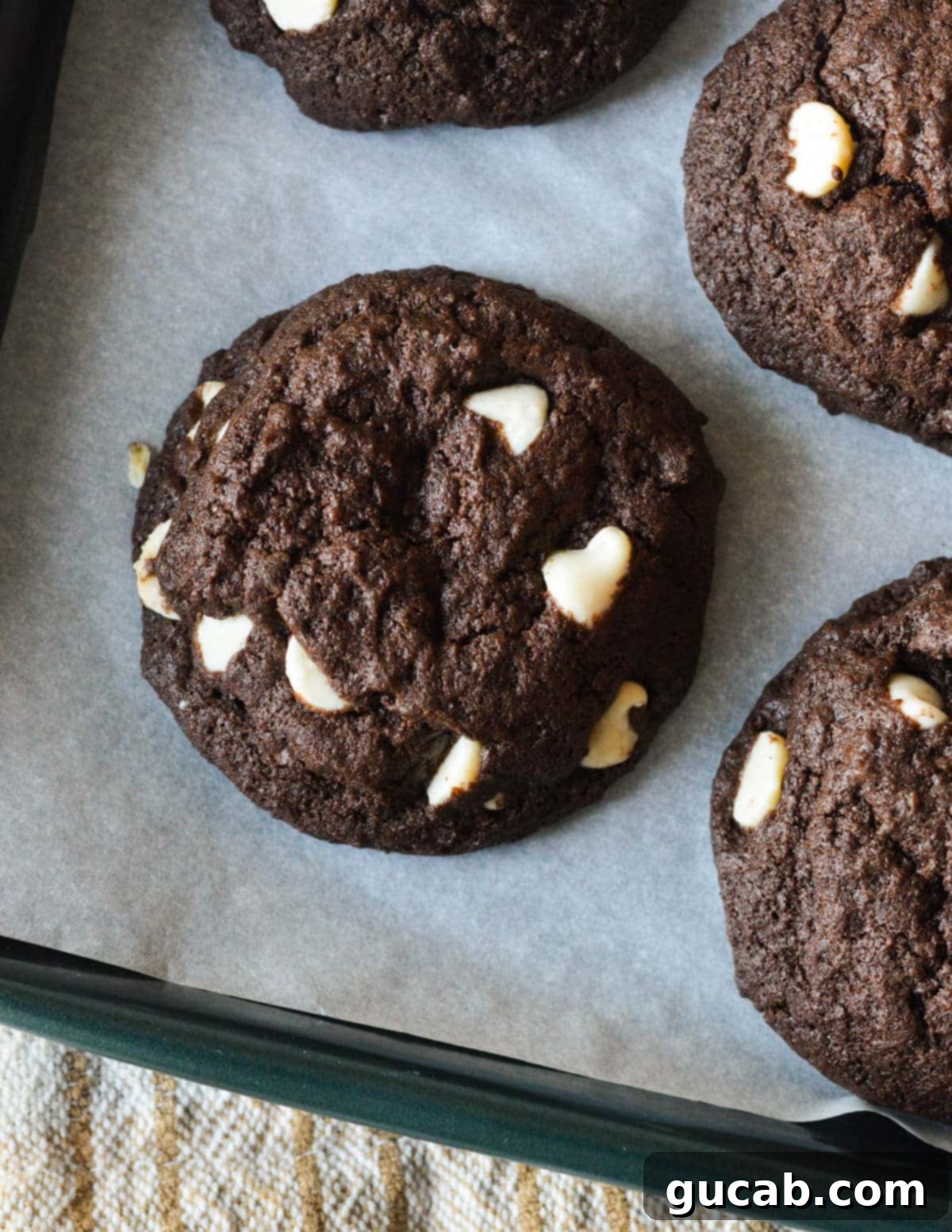 A single, perfectly baked chocolate peppermint cookie on a sheet pan, showcasing its rich dark color and white chocolate chunks.