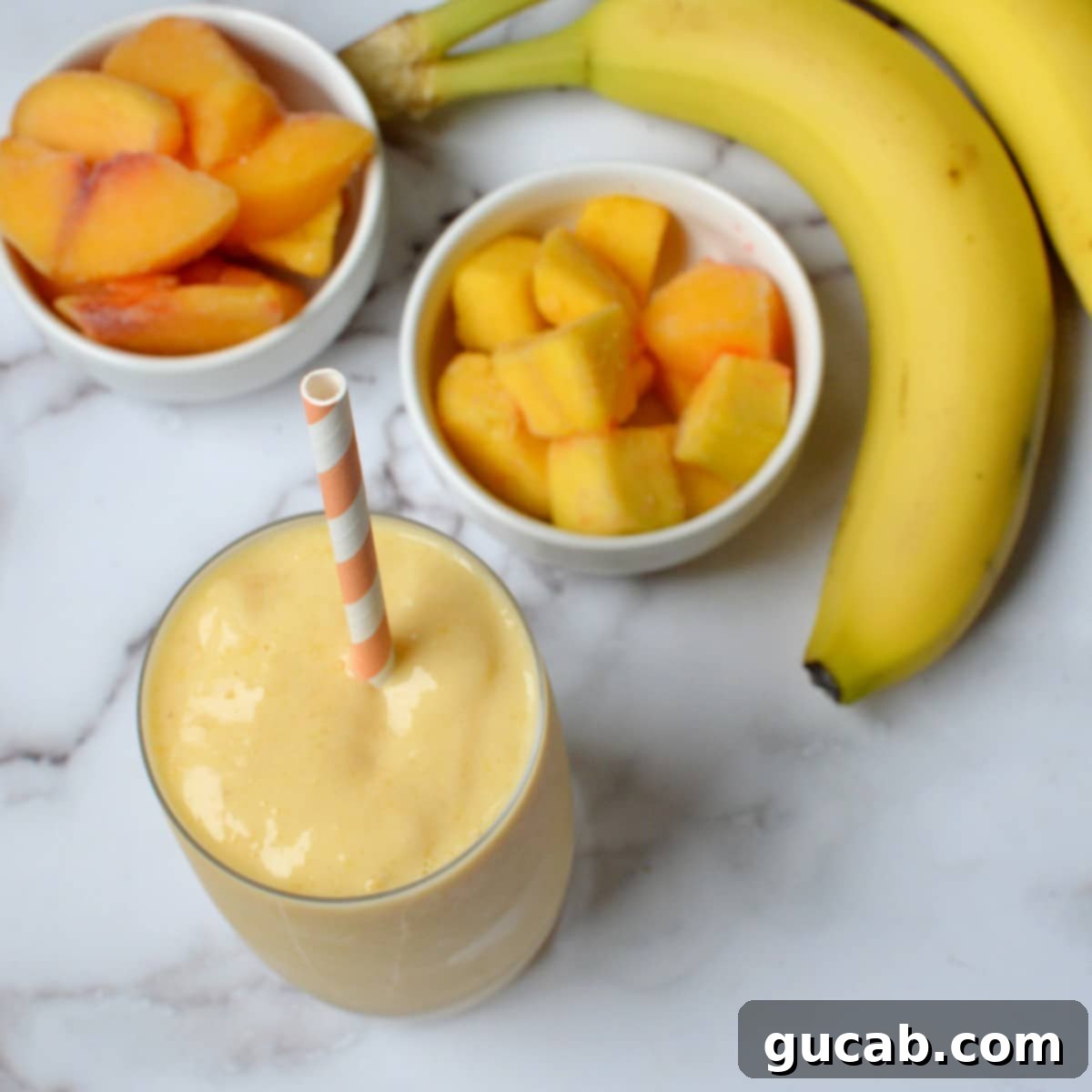 A peach smoothie with fruit in the background
