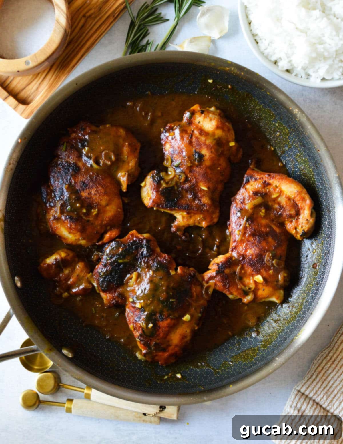 Blackened chicken thighs in a skillet, generously coated in a vibrant, sweet and tangy mustard sauce.