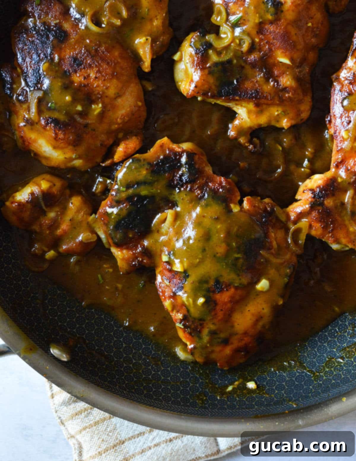 A close-up shot of perfectly caramelized chicken thighs glistening with sweet and tangy mustard sauce in a skillet, ready to be served.