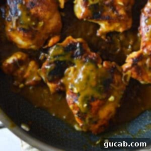 blackened chicken thighs in a skillet with a tangy mustard sauce.