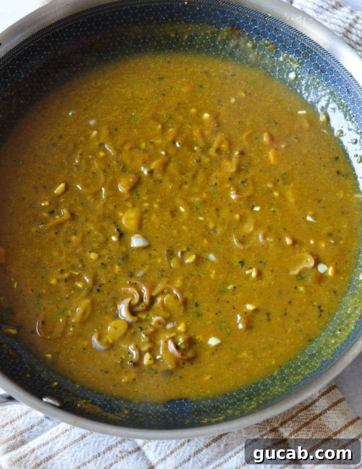 The sweet and tangy mustard sauce simmering in the skillet, thickening to a perfect consistency.
