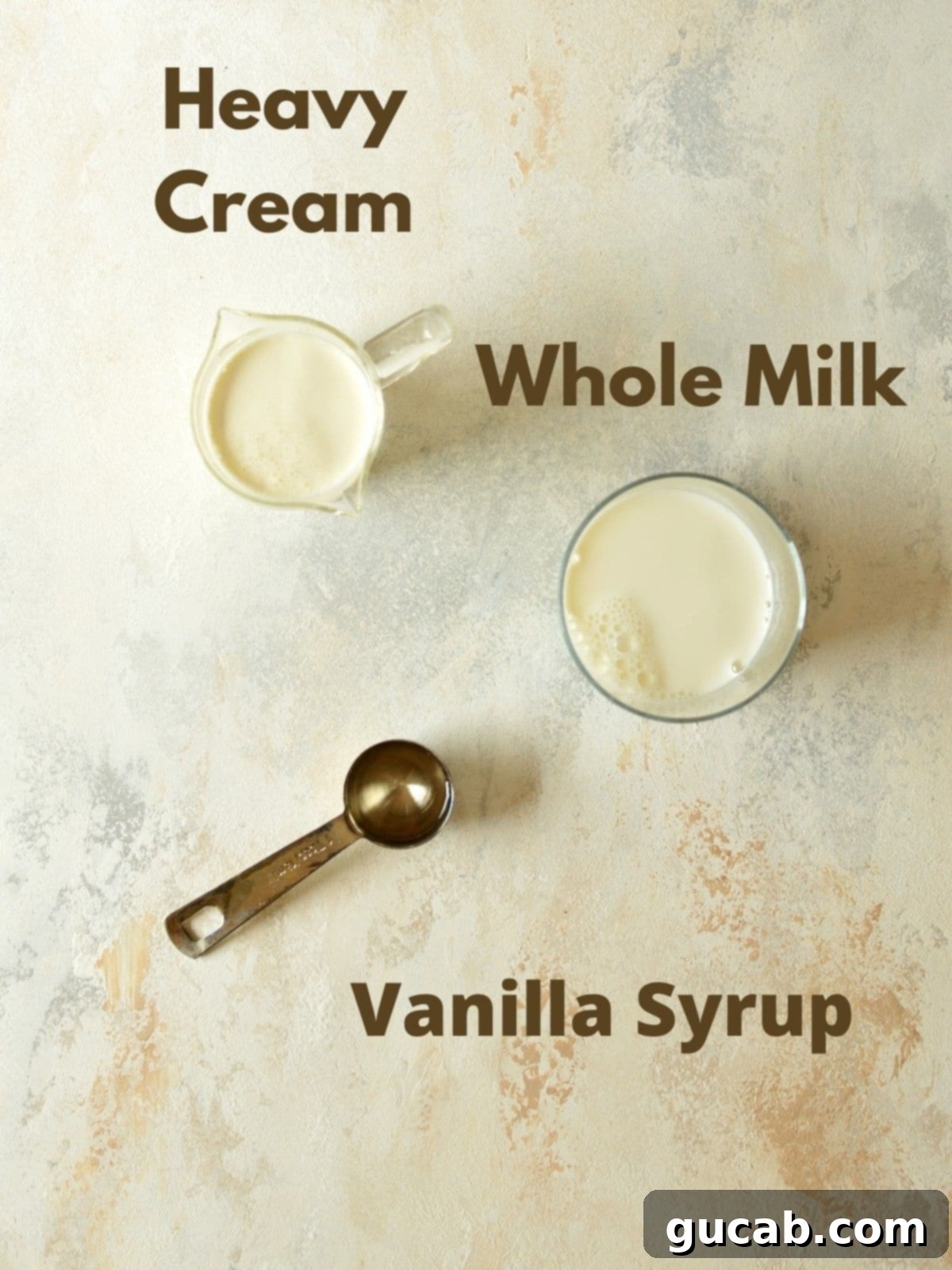 Three key ingredients for sweet cream cold foam: vanilla syrup, heavy cream, and 2% milk, displayed clearly for a recipe.