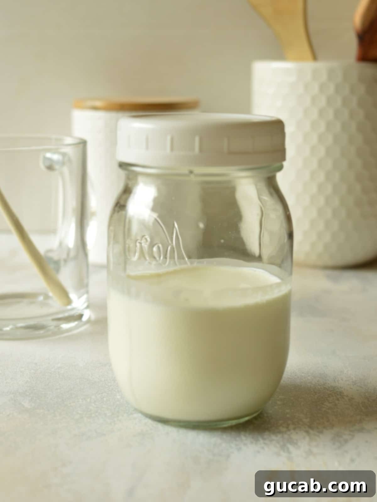 A clear glass jar containing heavy cream, vanilla syrup, and 2% milk, perfectly portioned for making sweet cream cold foam.