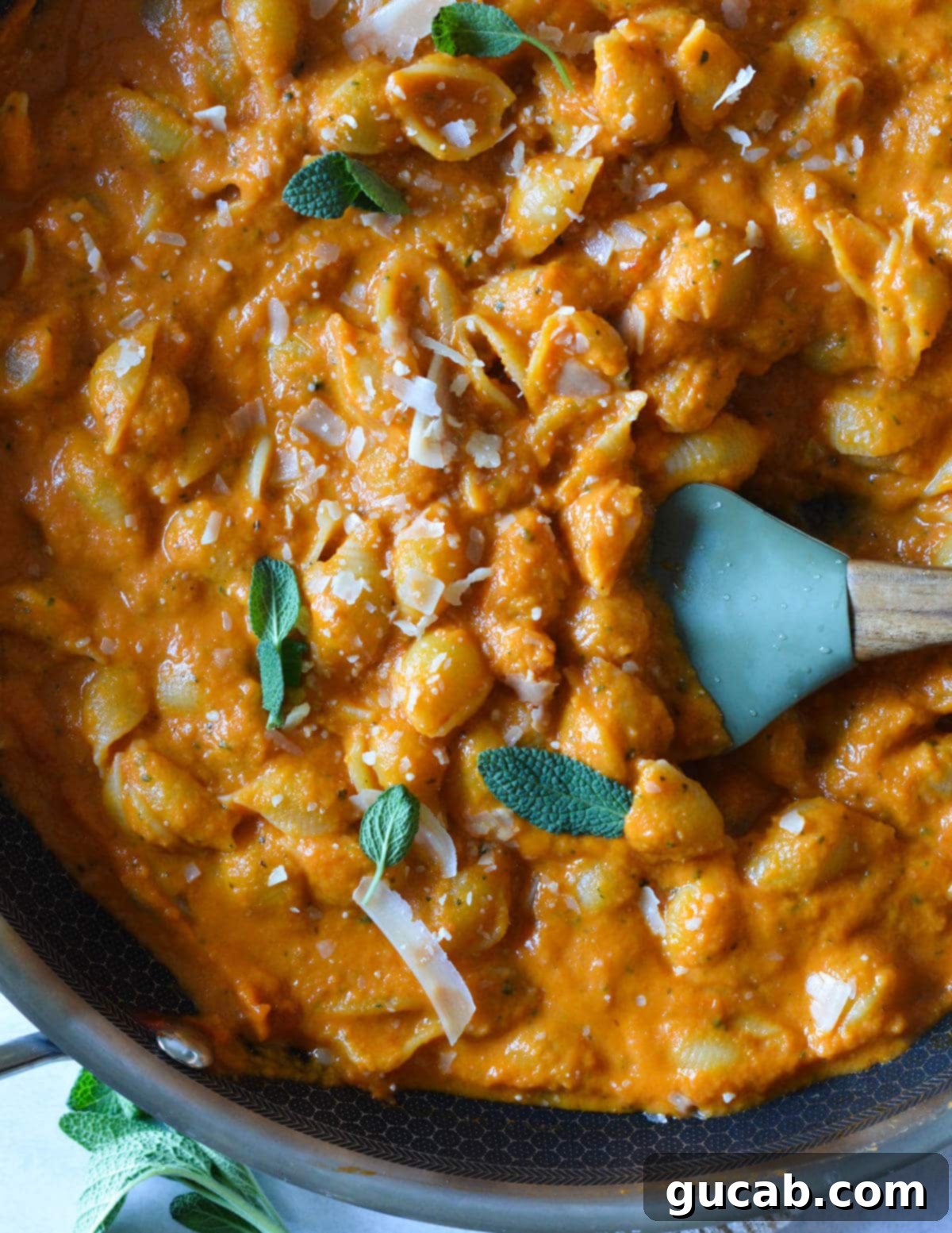 creamy pumpkin pasta in a skillet with a spatula in it. 