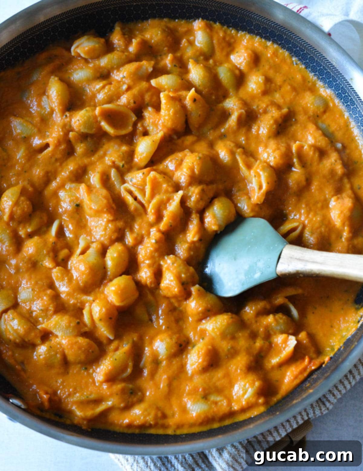 pumpkin pasta sauce with shells in a skillet with a spatula.