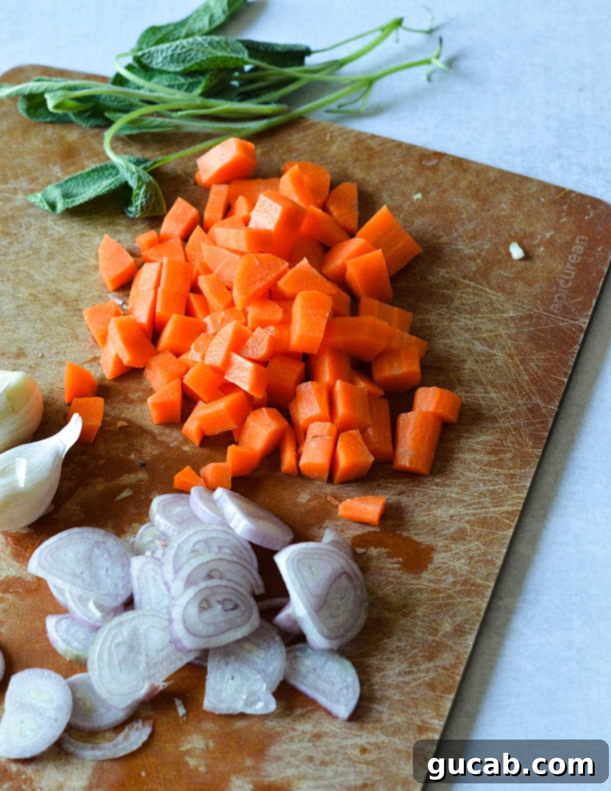 diced carrots, sliced shallots and garlic cloves on a cutting board.