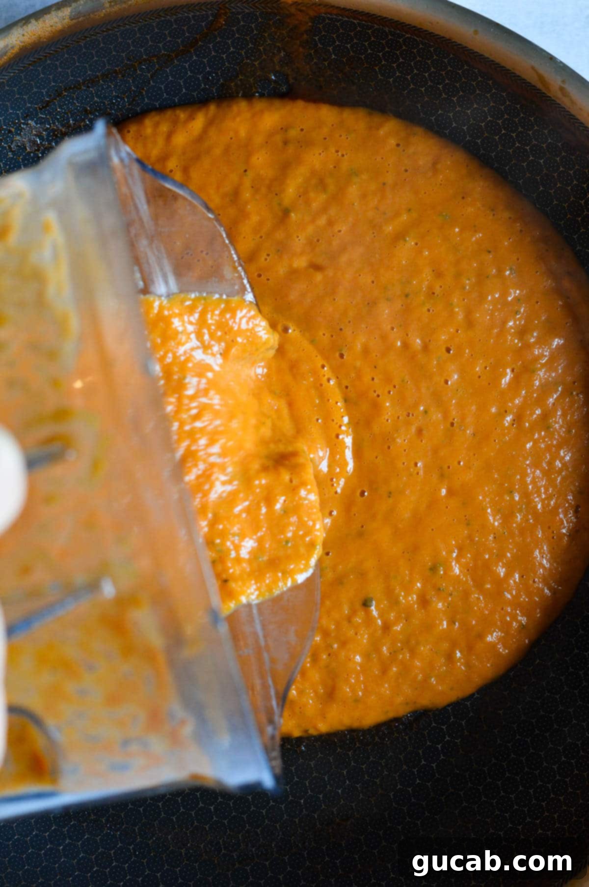 pouring pumpkin pasta sauce into a skillet. 