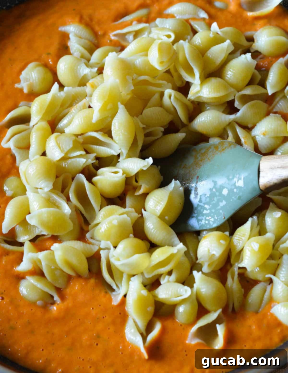 cooked pasta shells sitting in a skillet of pumpkin pasta sauce. 
