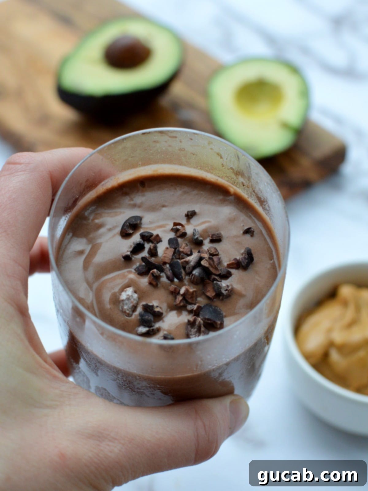 A close up of a chocolate peanut butter avocado smoothie in a glass
