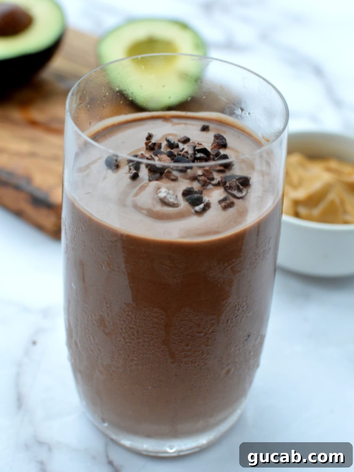 A peanut butter chocolate avocado smoothie with cocoa nibs on top