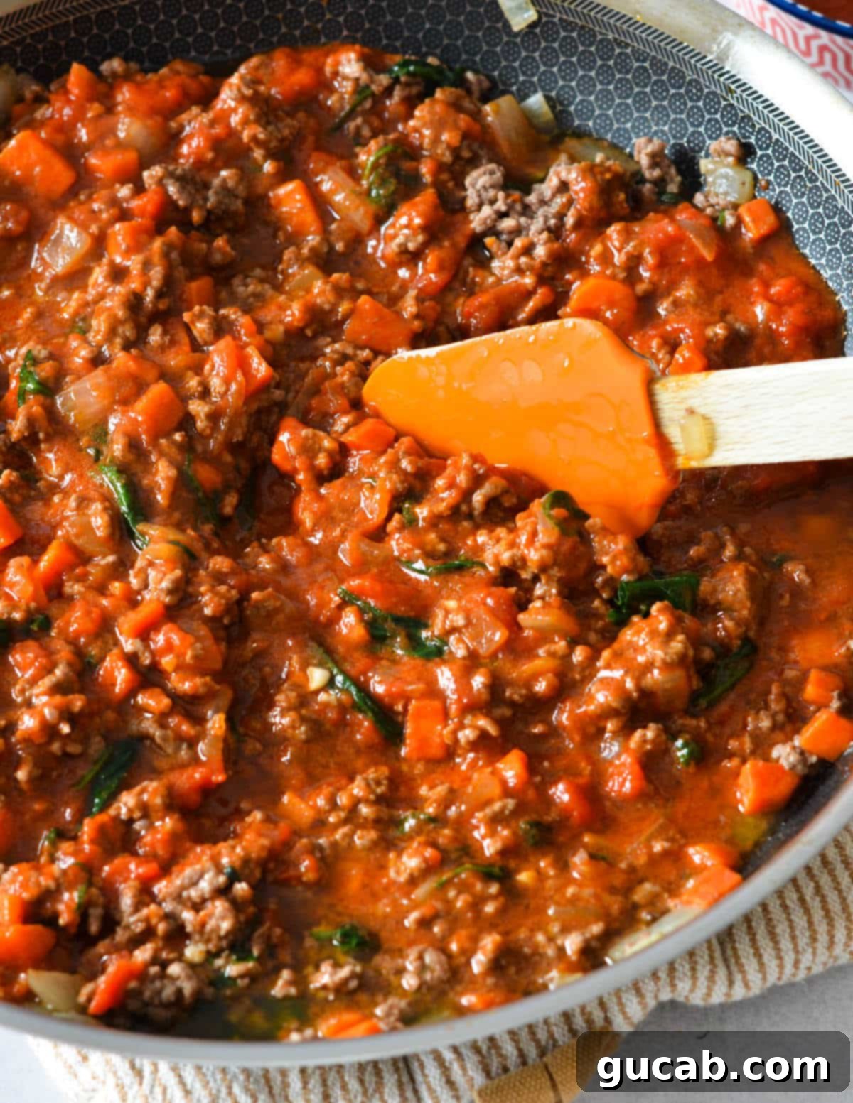 Bolognese-style meat sauce simmering in a skillet, rich and ready for filling.