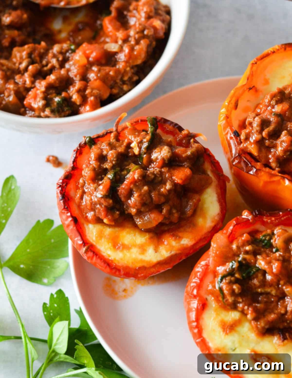 Lasagna bell peppers garnished with fresh herbs and an extra dollop of meat sauce on top.