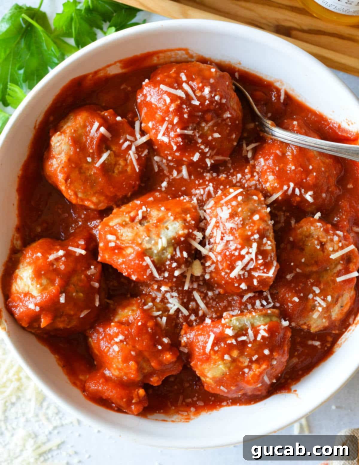 meatballs in marinara in a bowl with parmesan on top. 