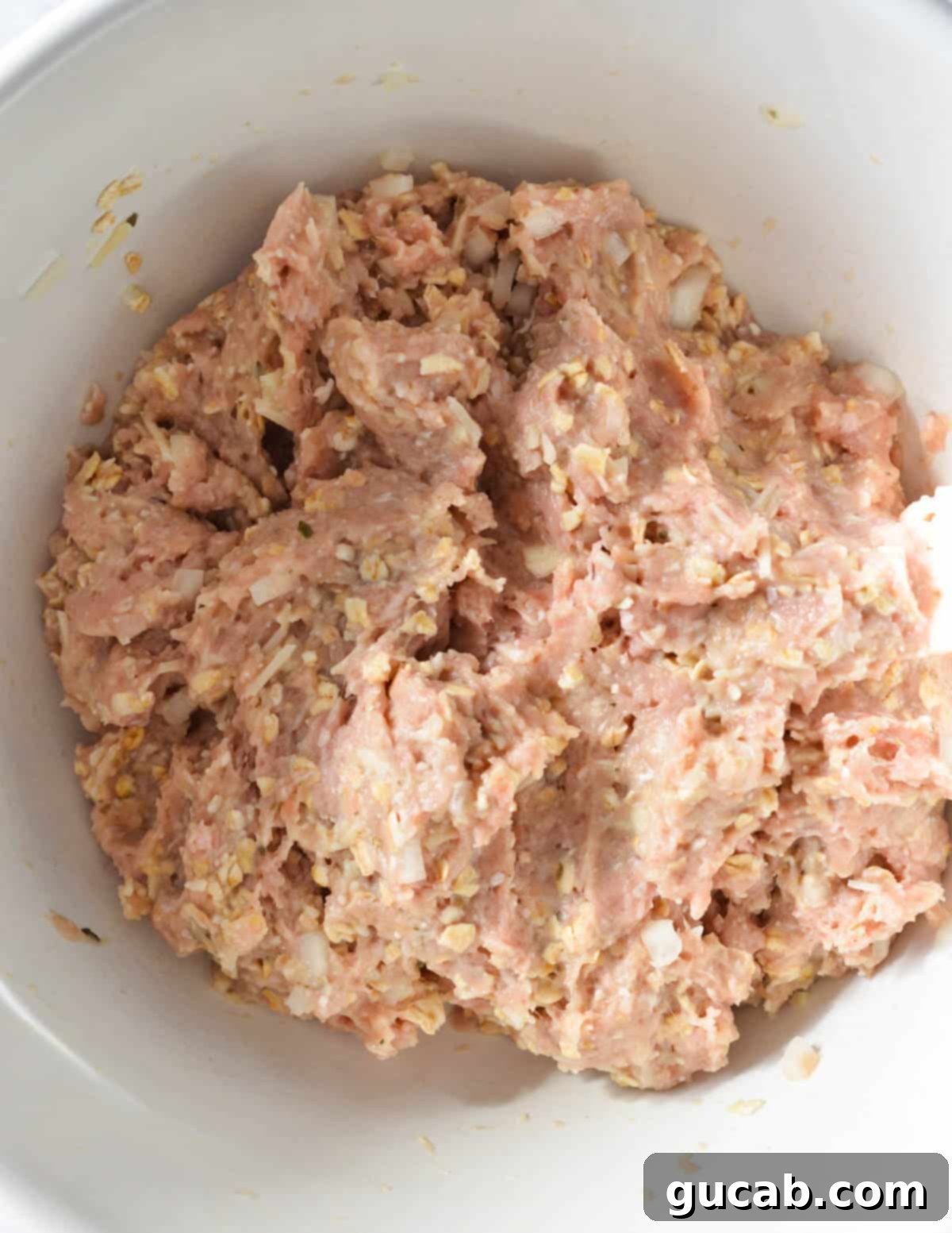 raw ground turkey mixture for meatballs in a bowl. 
