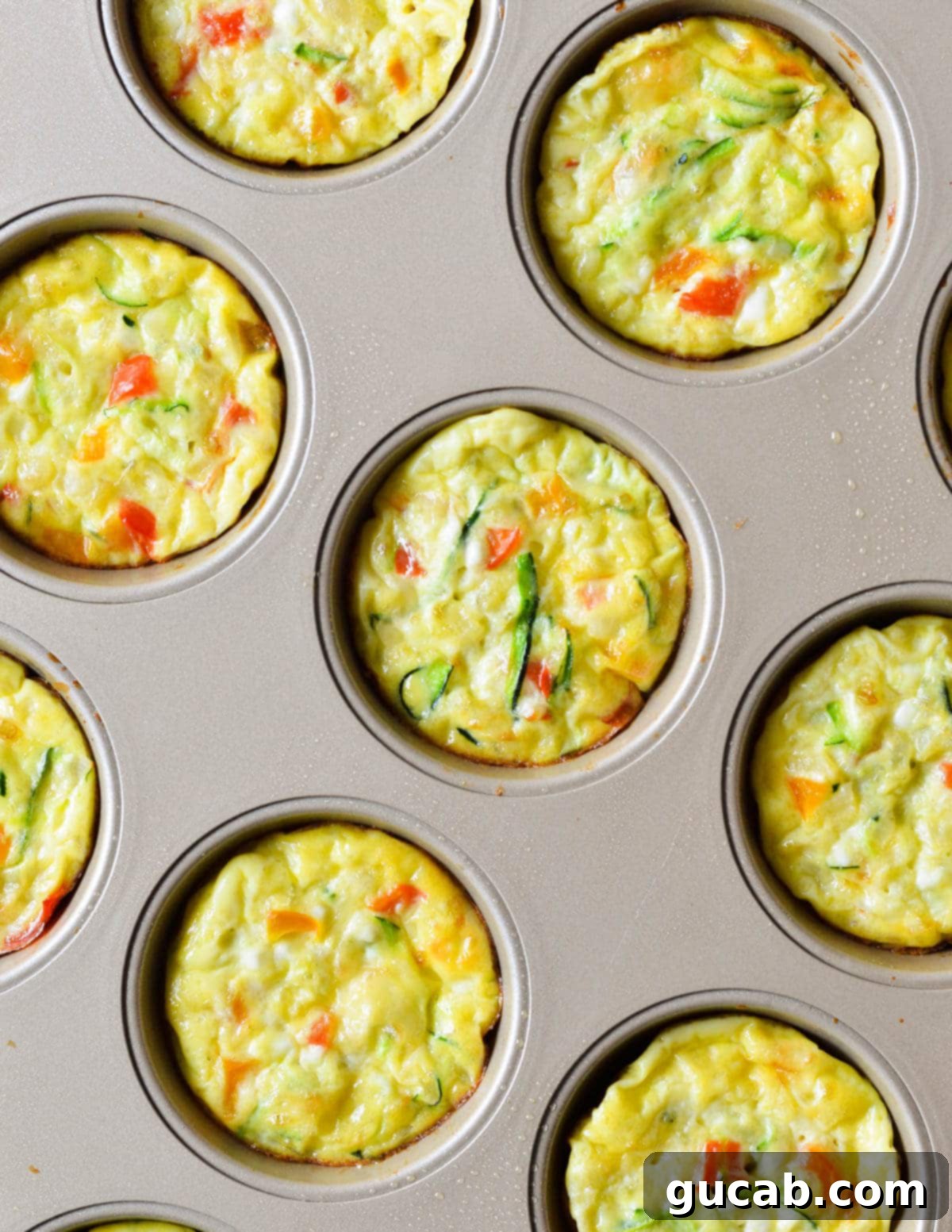 Baked egg muffins in a muffin tin, golden and perfectly risen, fresh out of the oven.