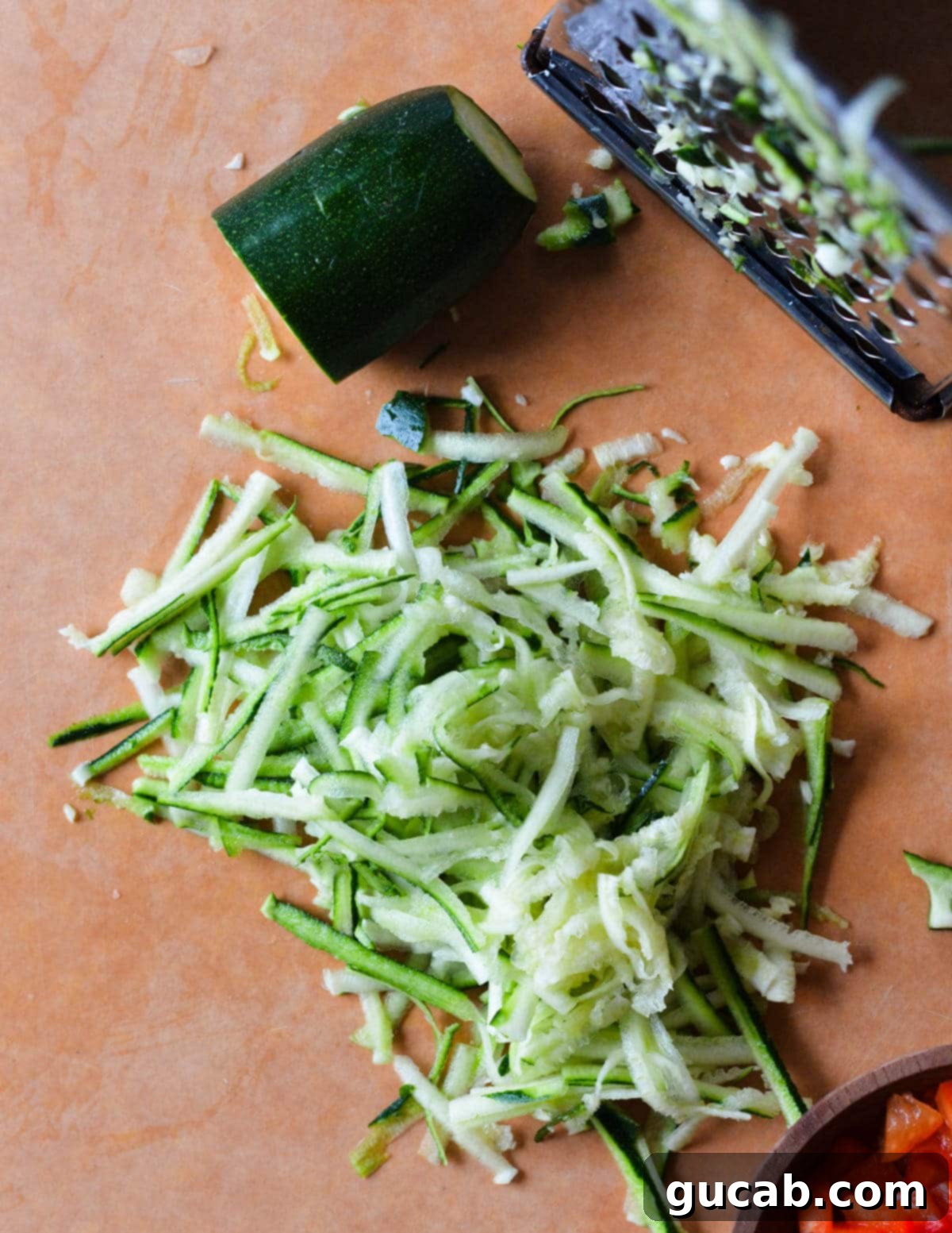 Freshly shredded zucchini on a cutting board, showing its fine texture before liquid is squeezed out.