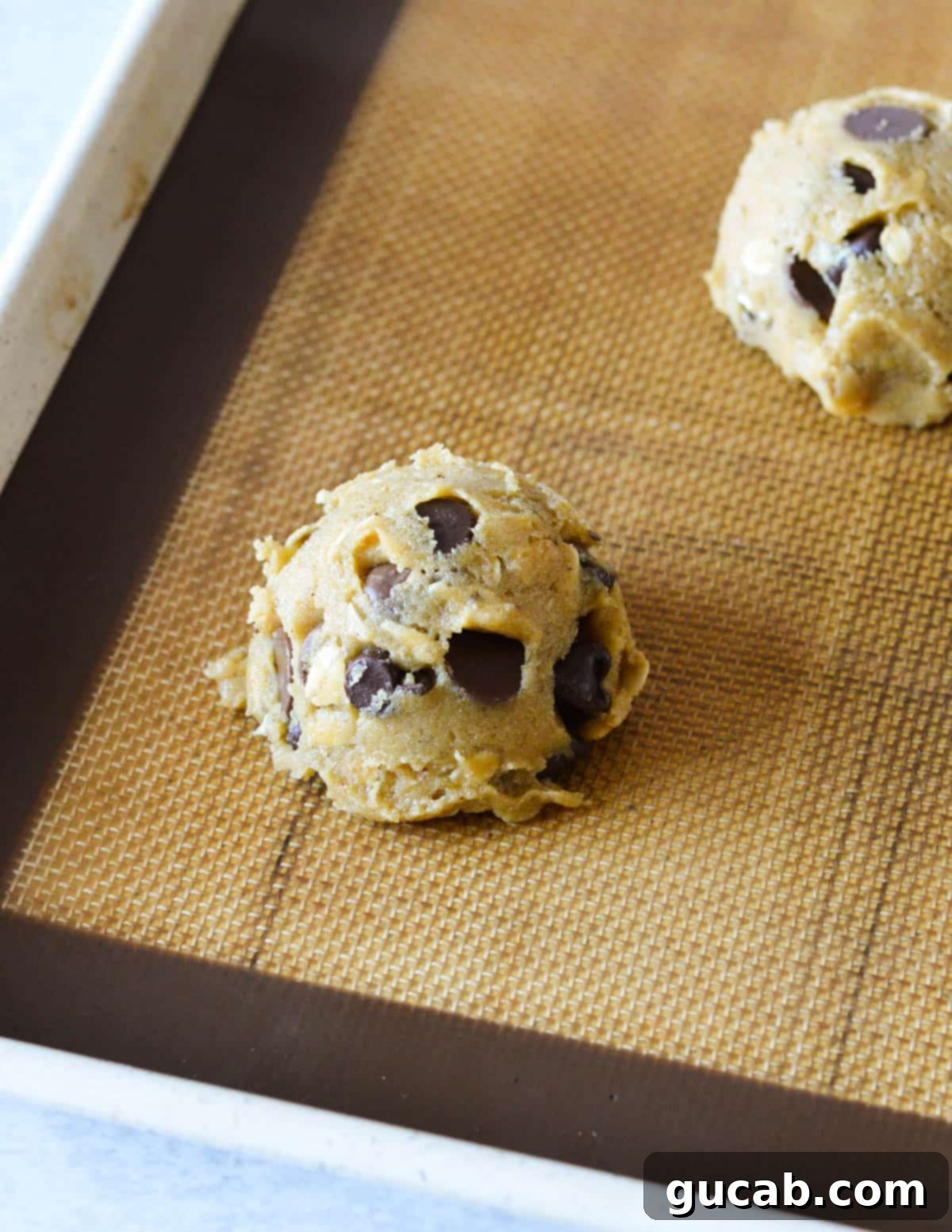 Nutty Brown Butter Chocolate Chip Cookies 15 A perfectly portioned scoop of chocolate chip cookie dough on a sheet pan, ready for baking.