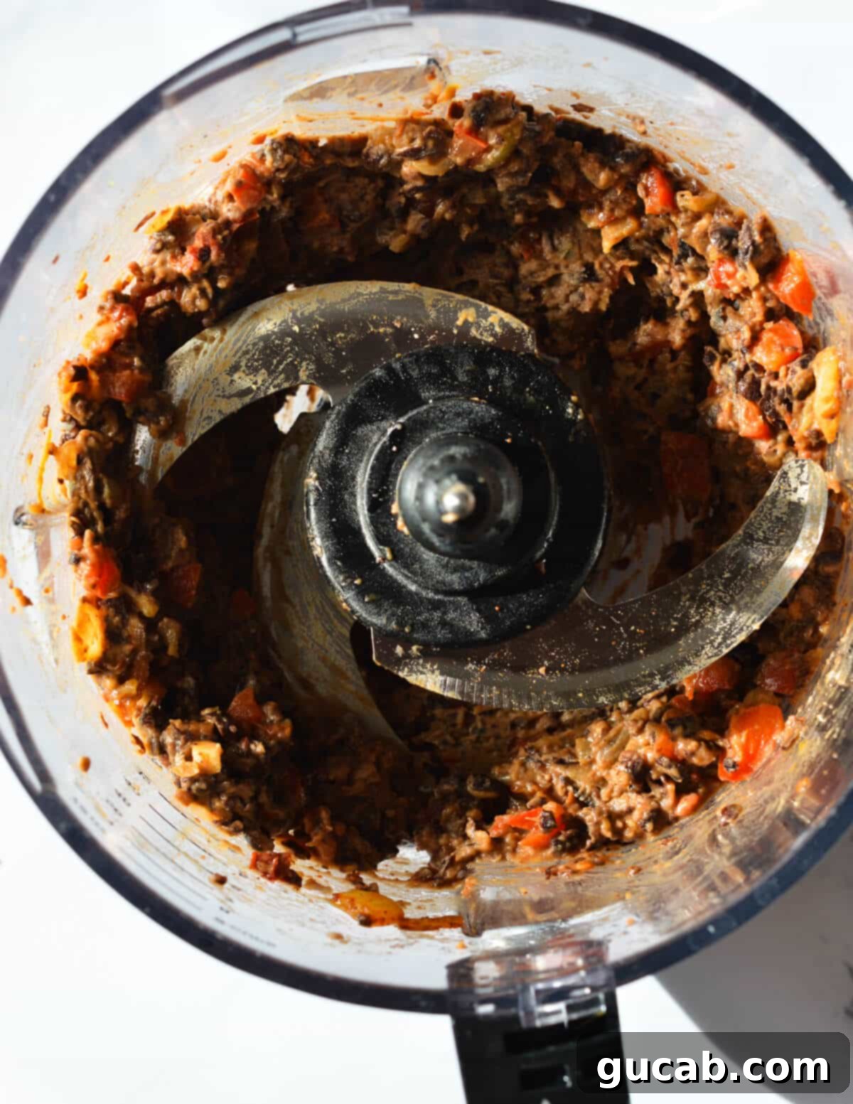 Chunky black bean and vegetable paste in a food processor, perfectly pulsed to retain some texture, which is crucial for creating robust and satisfying black bean burger patties.
