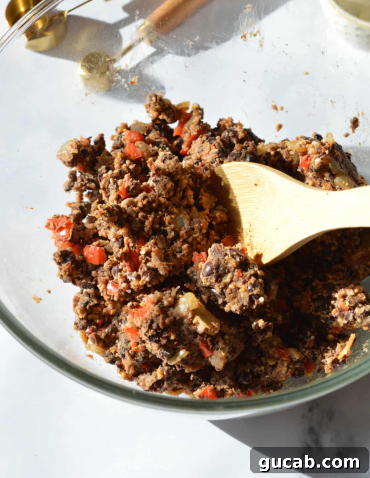 A large bowl filled with the perfectly combined black bean burger mixture, featuring a harmonious blend of whole beans, processed paste, cheese, and breadcrumbs, ready for forming into patties.