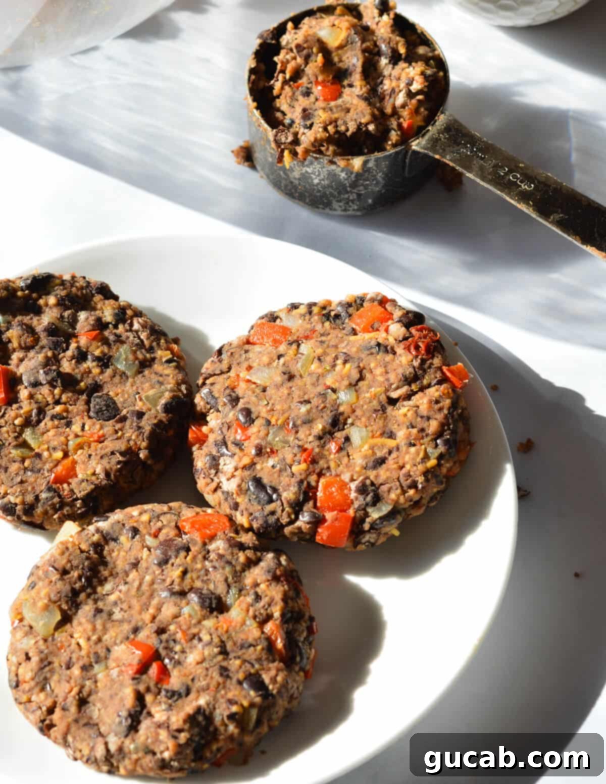 Six perfectly formed black bean burger patties, uniform in size and shape, neatly arranged on a plate, ready to be cooked or stored for later.