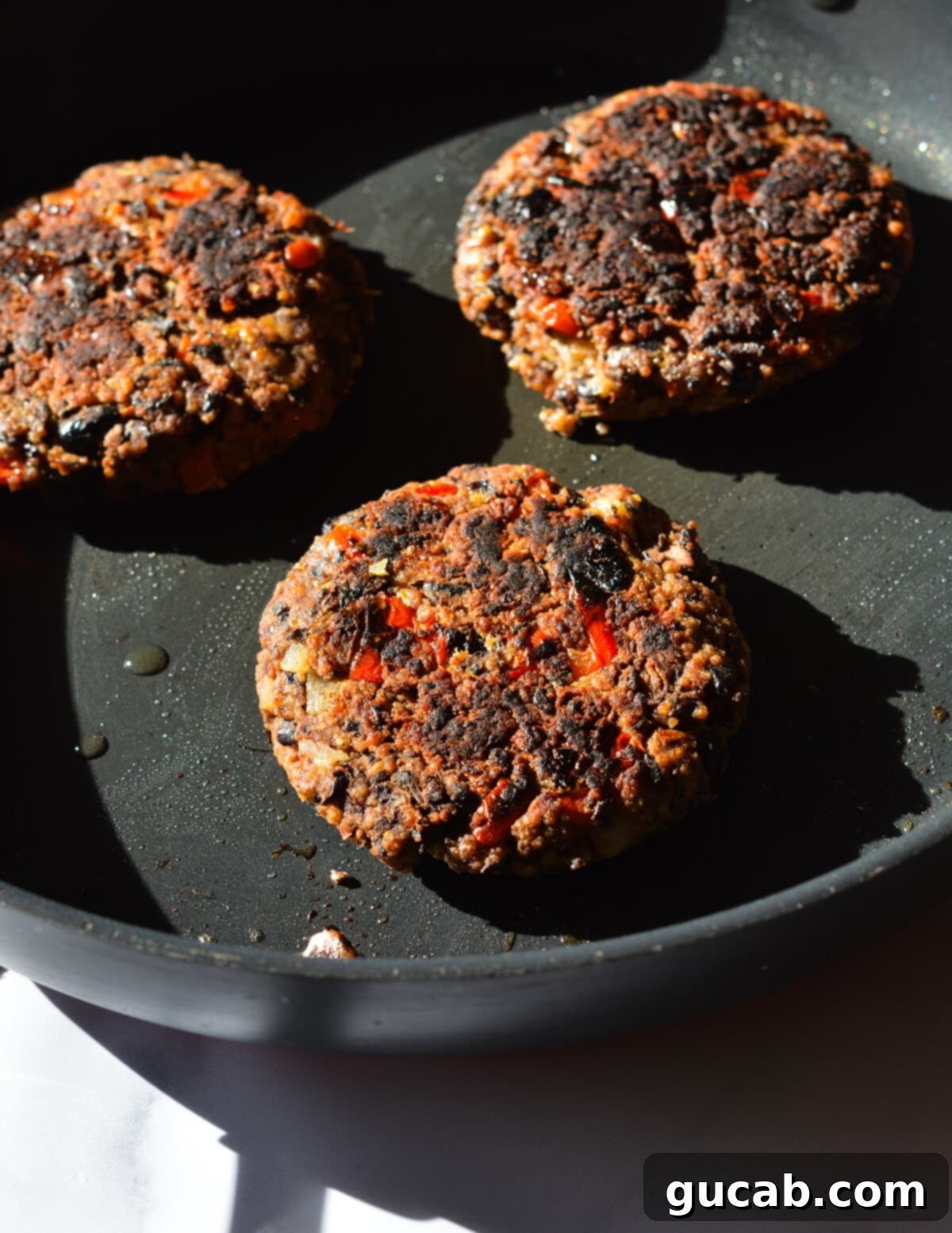 Perfectly caramelized and golden-brown black bean burger patties, removed from the skillet, showcasing their firm texture and ready to be assembled into delicious burgers.